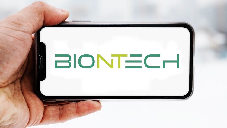 Hand, die ein Smartphone hält, auf dem das Logo des Unternehmens BioNTech zu sehen ist; Symbolbild für die "Aktie im Fokus"
