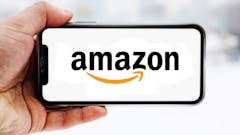 Hand, die ein Smartphone hält, auf dem das Logo des Unternehmens Amazon zu sehen ist; Symbolbild für die "Aktie im Fokus"