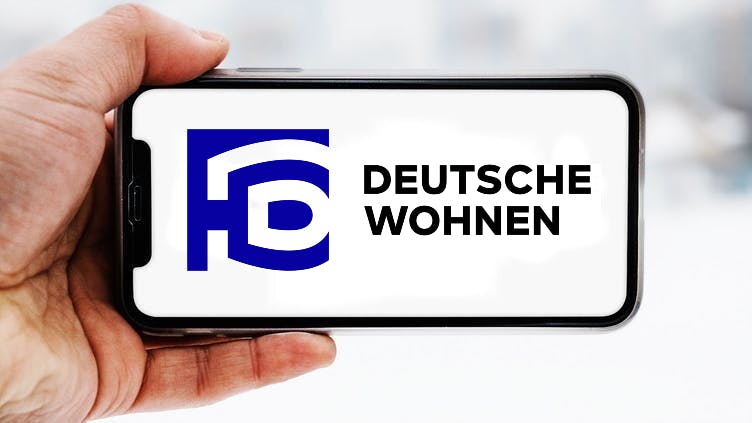 Hand, die ein Smartphone hält, auf dem das Logo des Unternehmens Deutsche Wohnen zu sehen ist; Symbolbild für die "Aktie im Fokus"