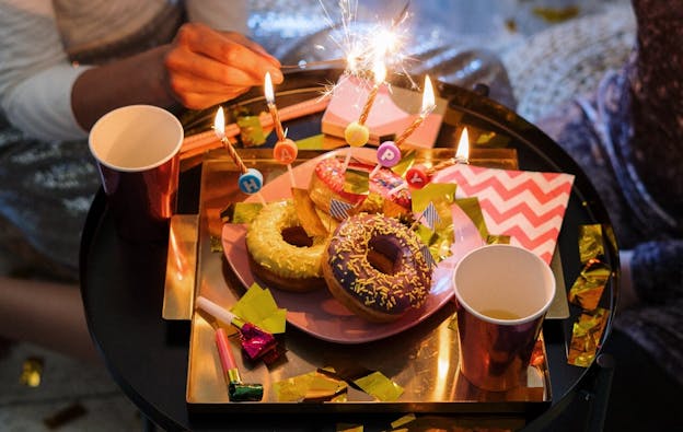 Happy-Birthday-Kerzen auf Donuts als Symbolbild für einen Geburtstag