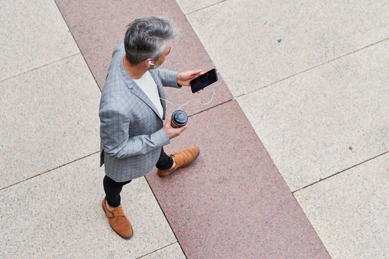 Mann auf Straße mit Mobiltelefon und Kaffee in der Hand