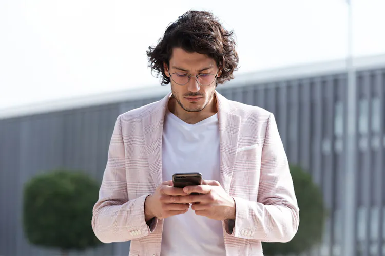 Gehender Mann, der auf das Smartphone schaut
