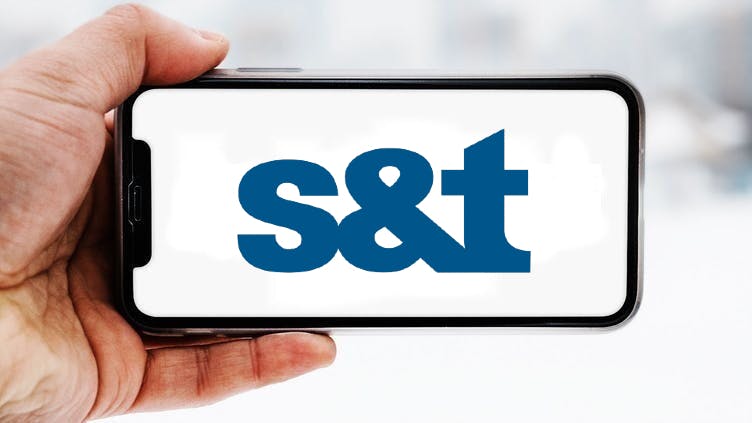 Hand, die ein Smartphone hält, auf dem das Logo des Unternehmens S&T zu sehen ist; Symbolbild für die "Aktie im Fokus"