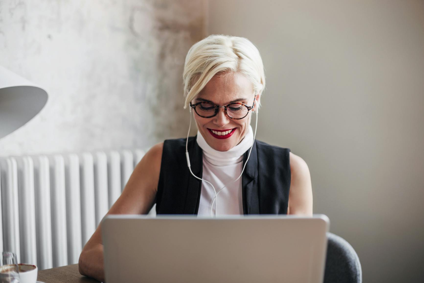 Lächelnde Frau, die bei Tisch sitzt und auf den Laptop schaut