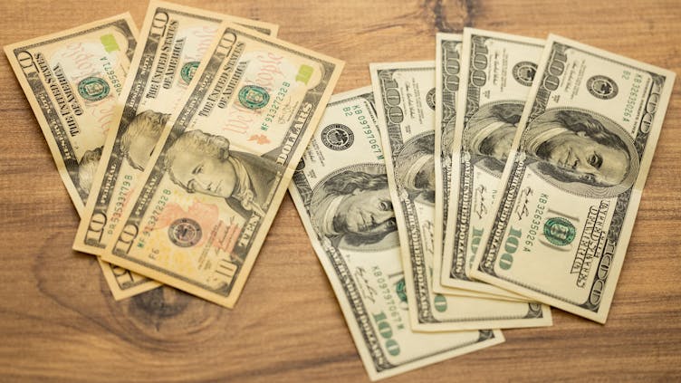 Geldscheine verschiedener Wertigkeiten liegen auf einem Holztisch, um die Inflation darzustellen; Symbolbild für weekly Ausgabe "… und sie dreht sich doch"