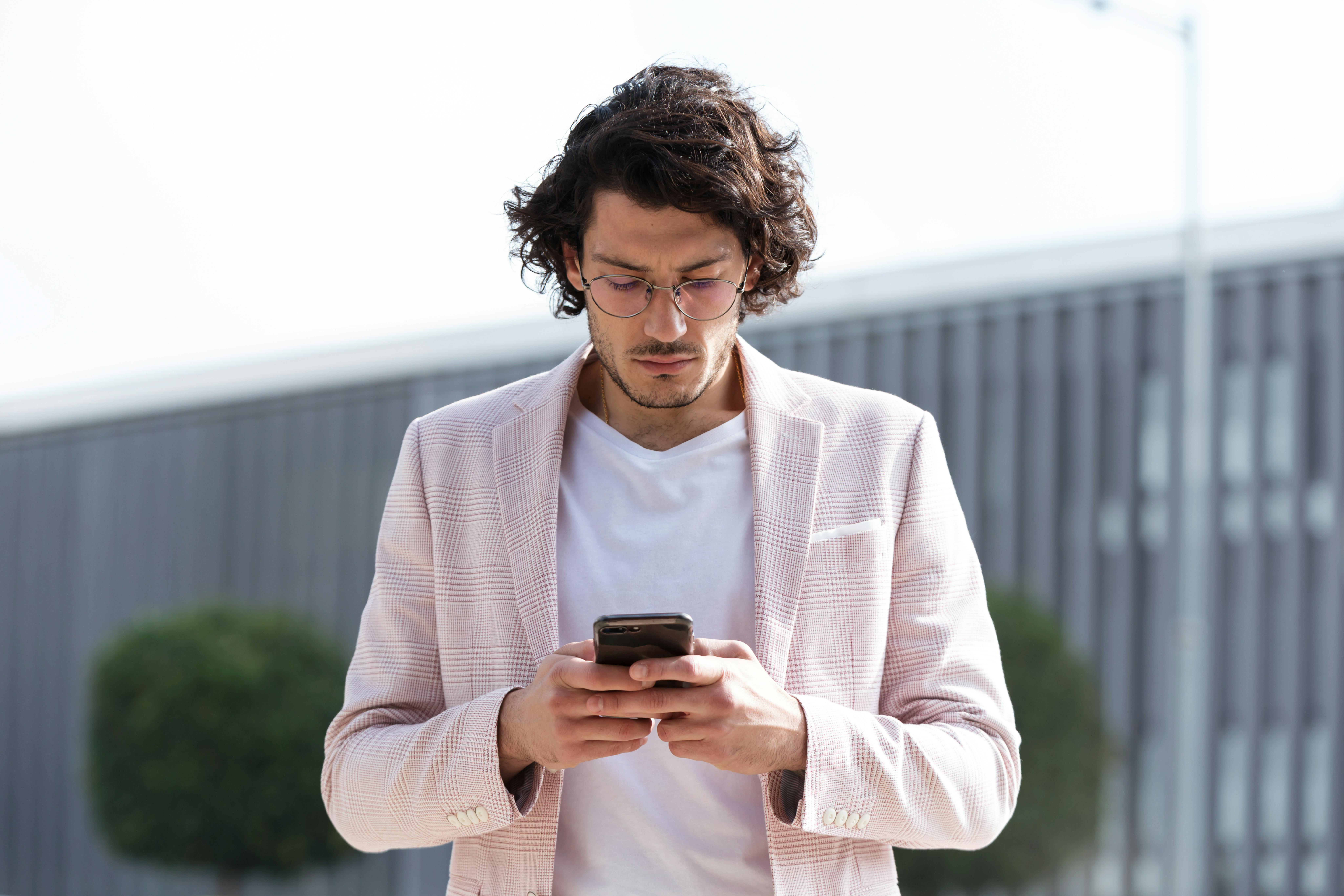 Gehender Mann, der auf das Smartphone schaut