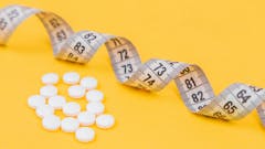 maßband-mit-tabletten-gelber-hintergund-pharma