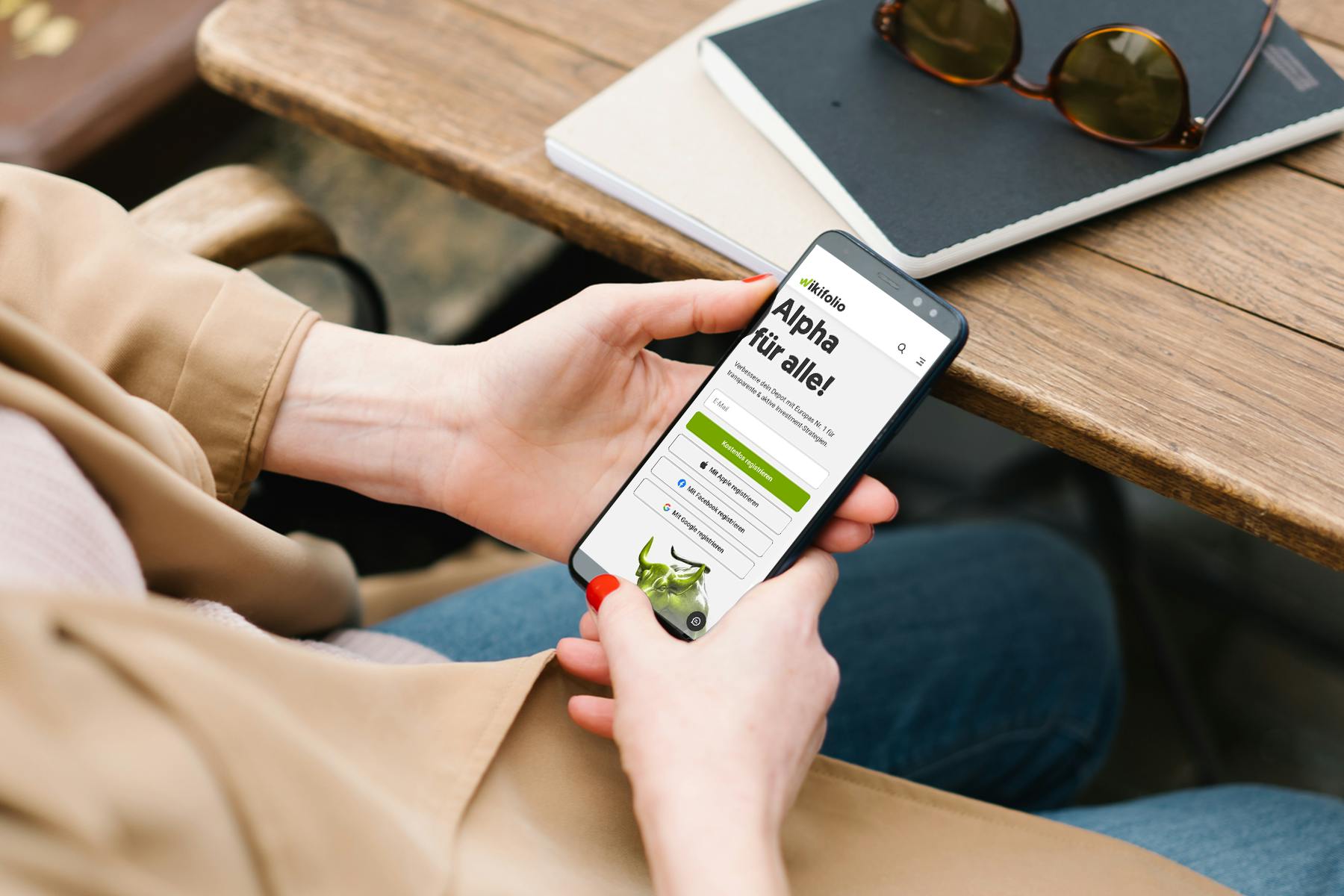 Frau, die auf Smartphone, welches die Website wikifolio.com anzeigt, schaut 